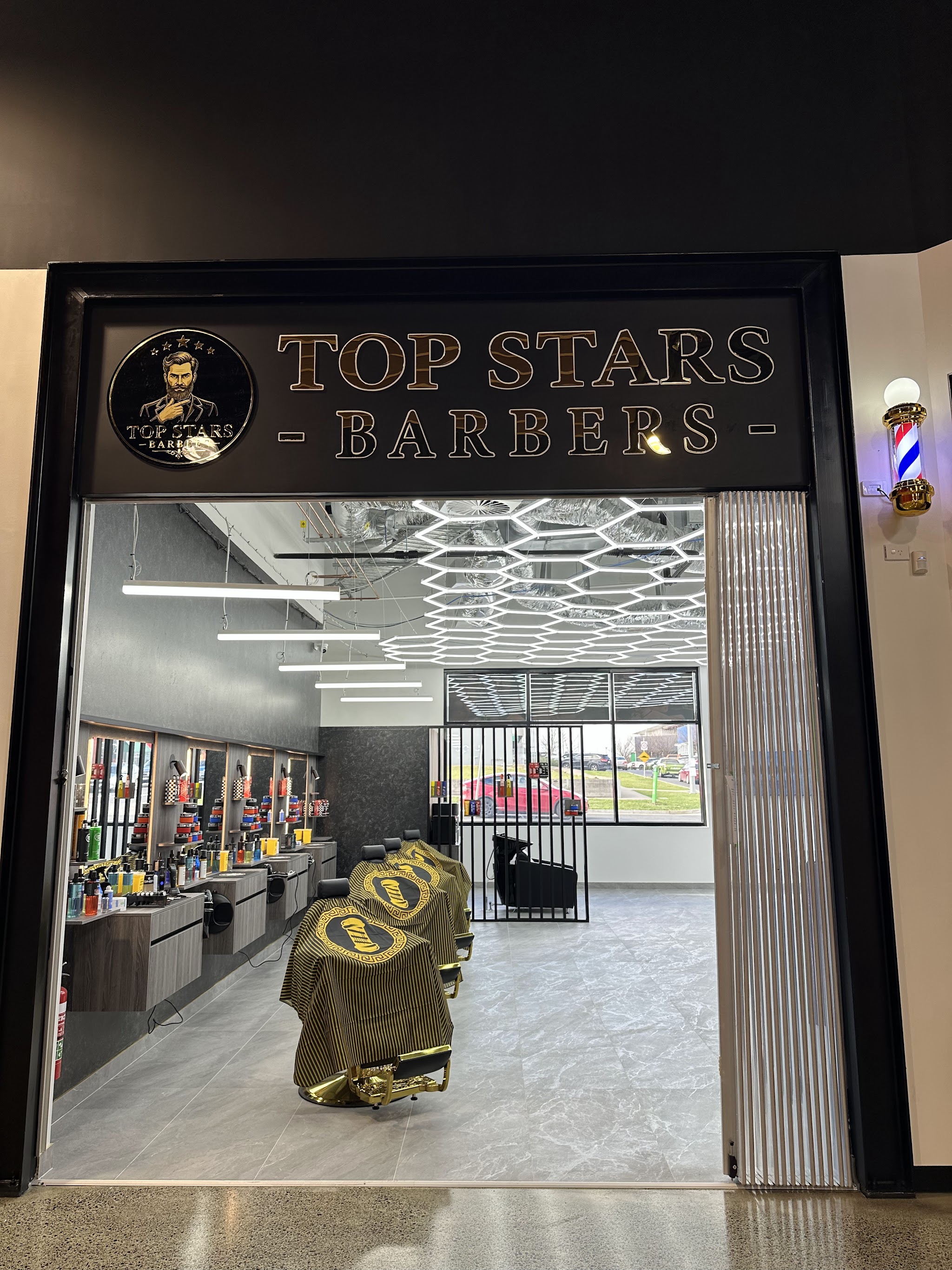 The Top Stars Barbers shopfront with its gold lettered sign, barber pole and a row of gold chairs inside